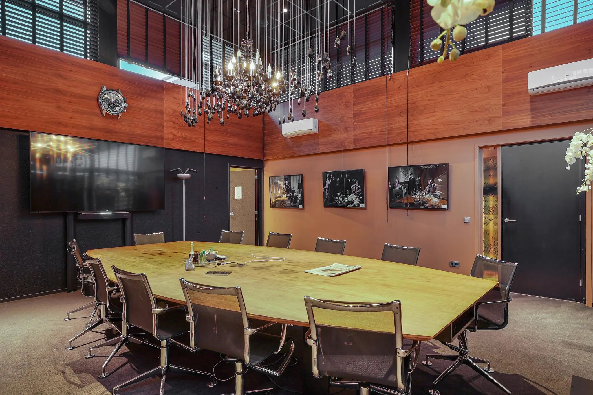 Vergaderruimte met een grote houten tafel, moderne stoelen, een kroonluchter en wanddecoratie aan de Oude Utrechtseweg.